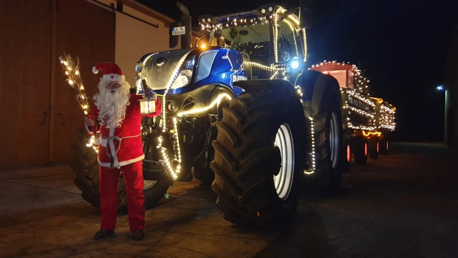 NM- Nerchau-Mutzschener - Landwirtschaft - Ein blauer, weihnachtlich geschmückter Traktor parkt nachts neben einer als Weihnachtsmann verkleideten Person.